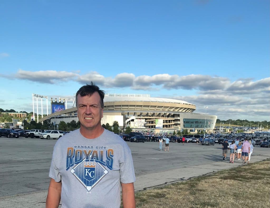 Paul Poppe smiling standing outside of the Kansas City Royals stadium.