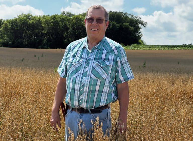 Scott Heinemann smiling and standing in a field.
